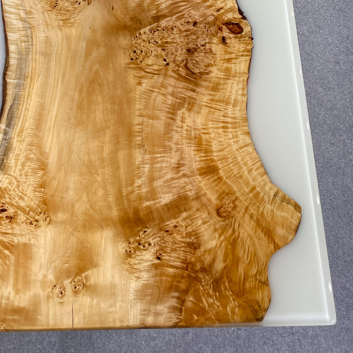 Wooden cutting board with a white resin base on a gray surface