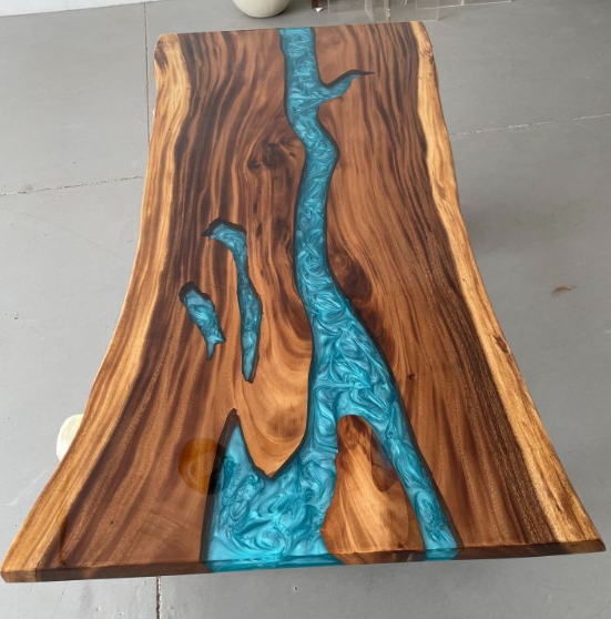 Wooden table with blue resin inlay on a gray floor