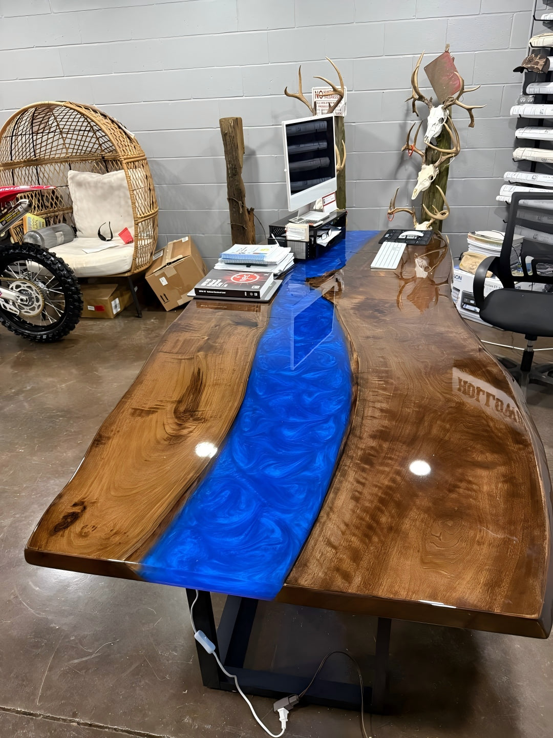 Ocean-inspired epoxy river table illuminated by LED lights at night, creating a luxurious deep-sea glow across the glossy walnut surface.