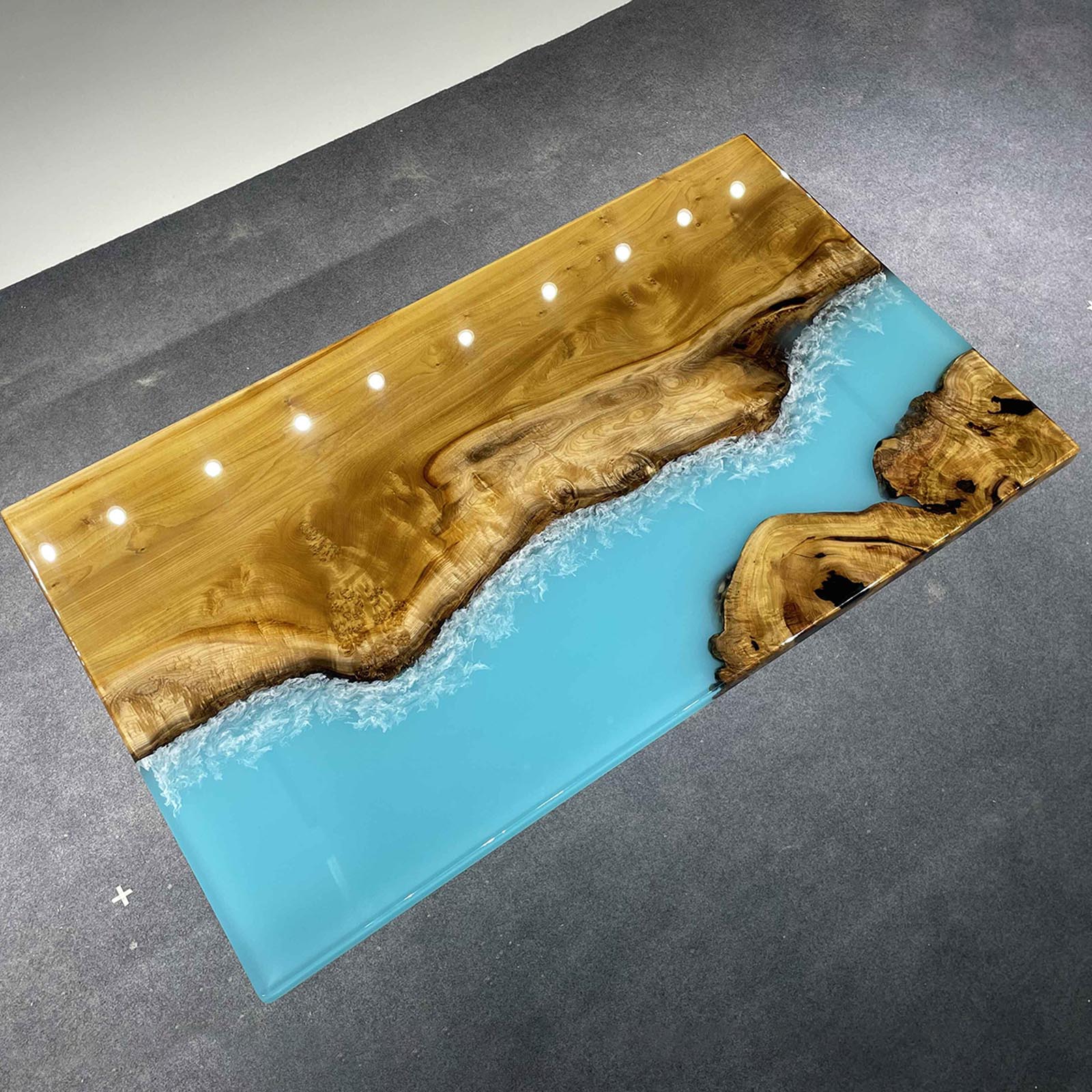 Modern coffee table featuring golden camphor wood and blue-white epoxy wave pattern.