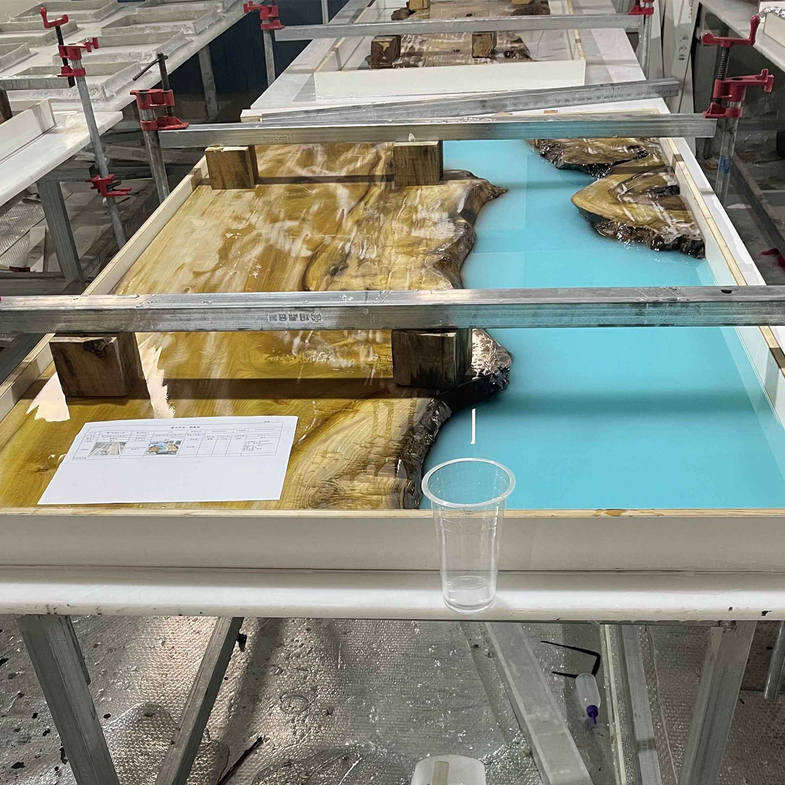 Close-up of blue and white epoxy resin waves blending with golden camphor wood grain.