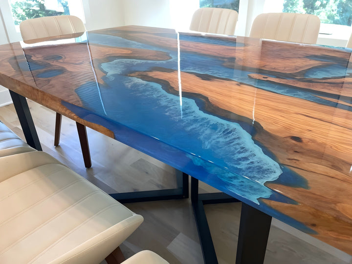 Live edge olive wood table featuring deep ocean blue epoxy river design