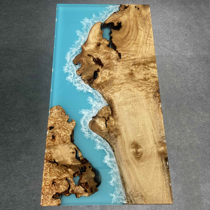 Custom wood and resin table featuring golden camphor wood and realistic ocean waves in clear blue epoxy.