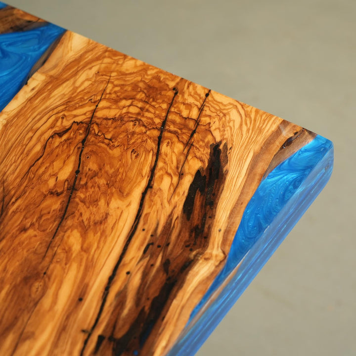 Custom olive wood blue epoxy river dining table placed in modern Malibu-style dining room