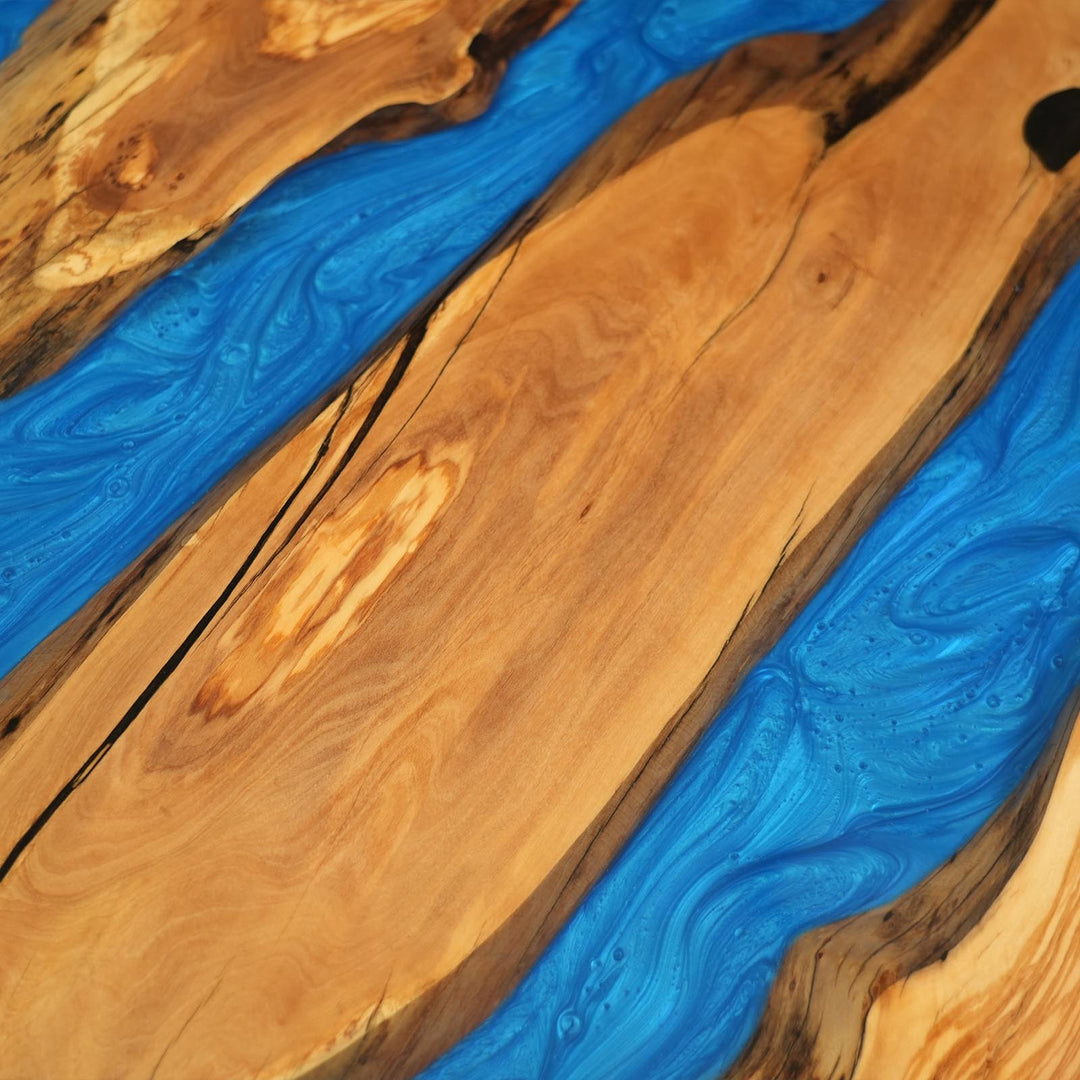 Modern metal base supporting custom olive wood epoxy river dining table