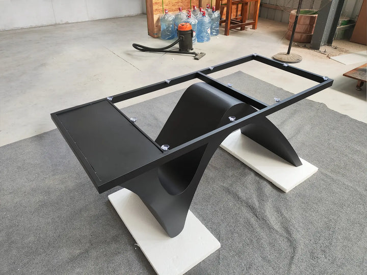 Angled side view of the MTL20 curved X-shaped metal table base showing its sculptural support structure