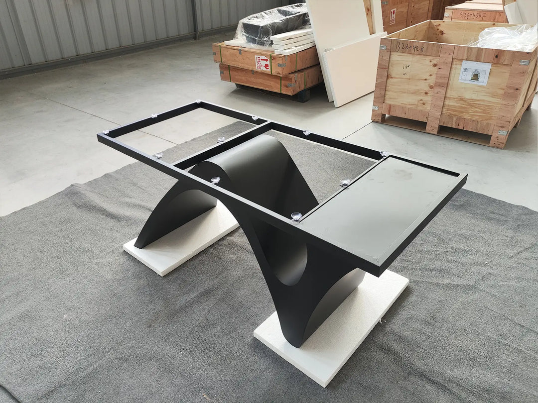 Three-quarter view of the MTL20 sculptural metal table base showing its curved X-shaped design and silver-tone floor supports