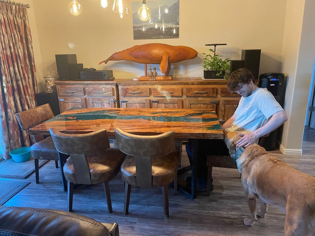 Close-up of olive wood and clear epoxy resin layer showing natural wood grain and glossy surface finish on a custom epoxy river dining table.