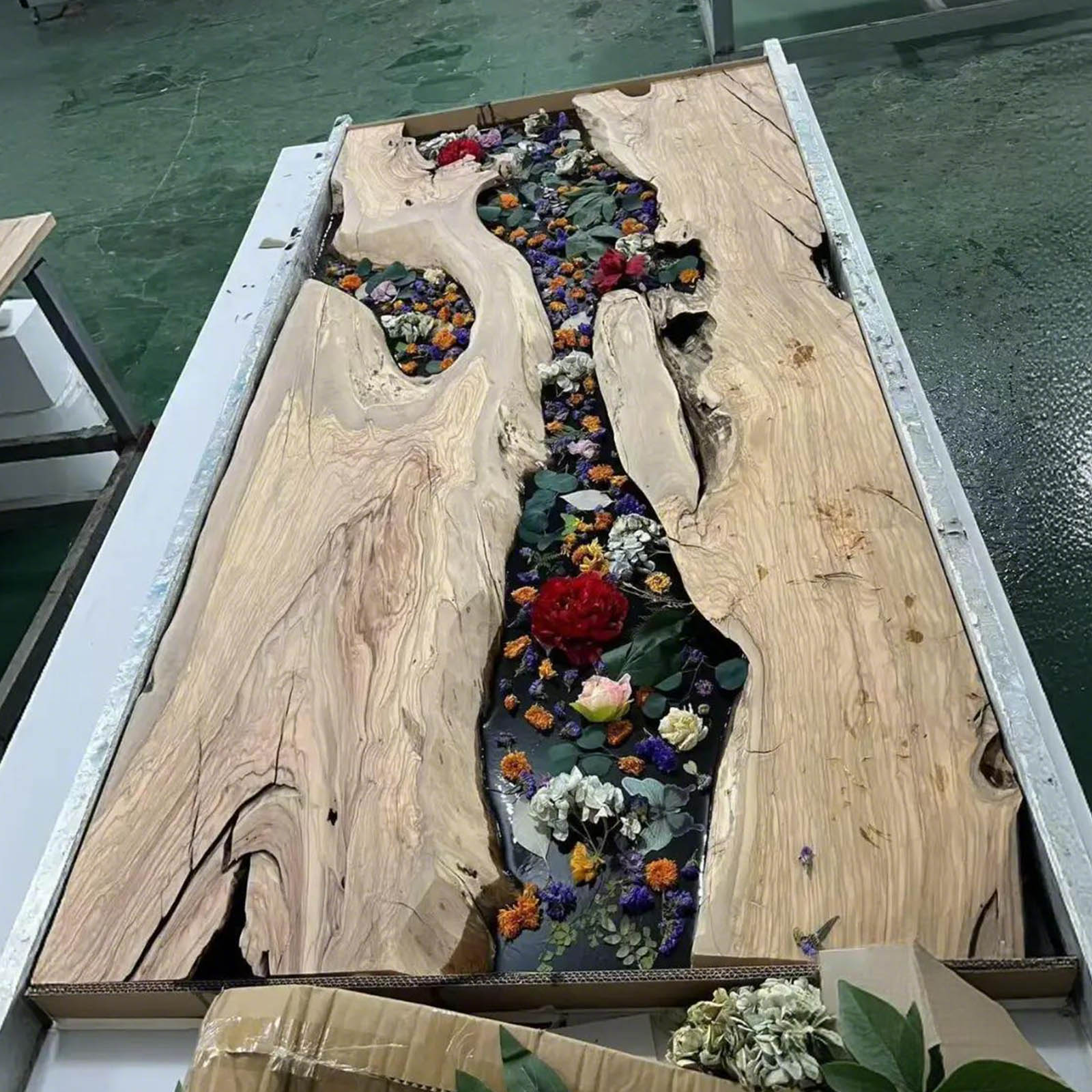 Side angle view of California Luxe olive wood dining table with black epoxy river.