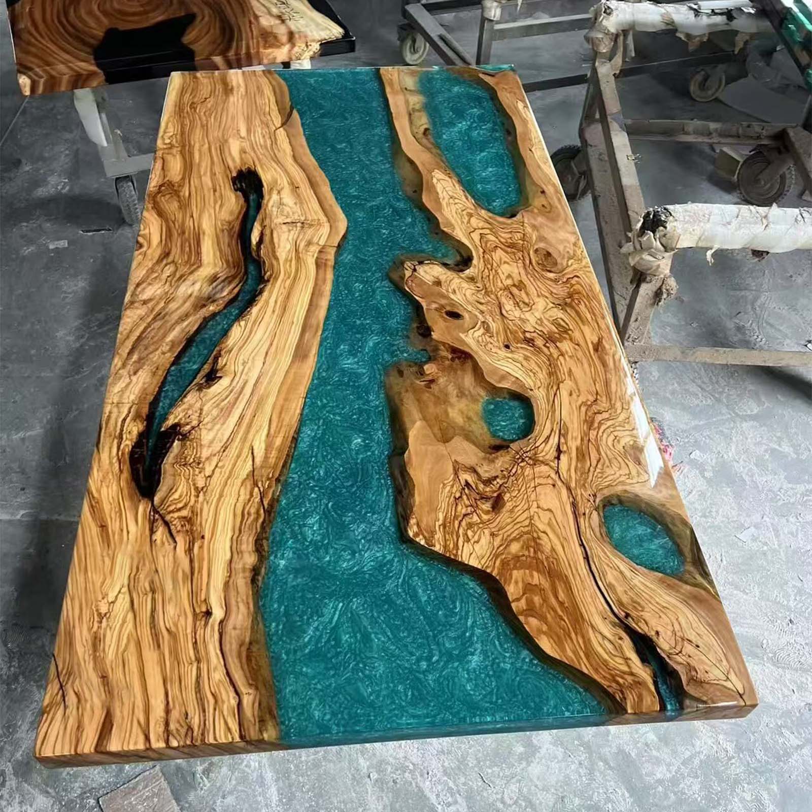 Luxury handcrafted olive wood epoxy river table with glossy surface and deep lagoon color.