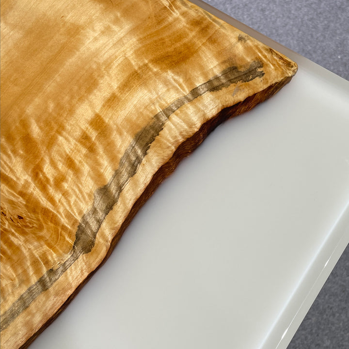 Wooden cutting board with a natural grain pattern on a white surface.