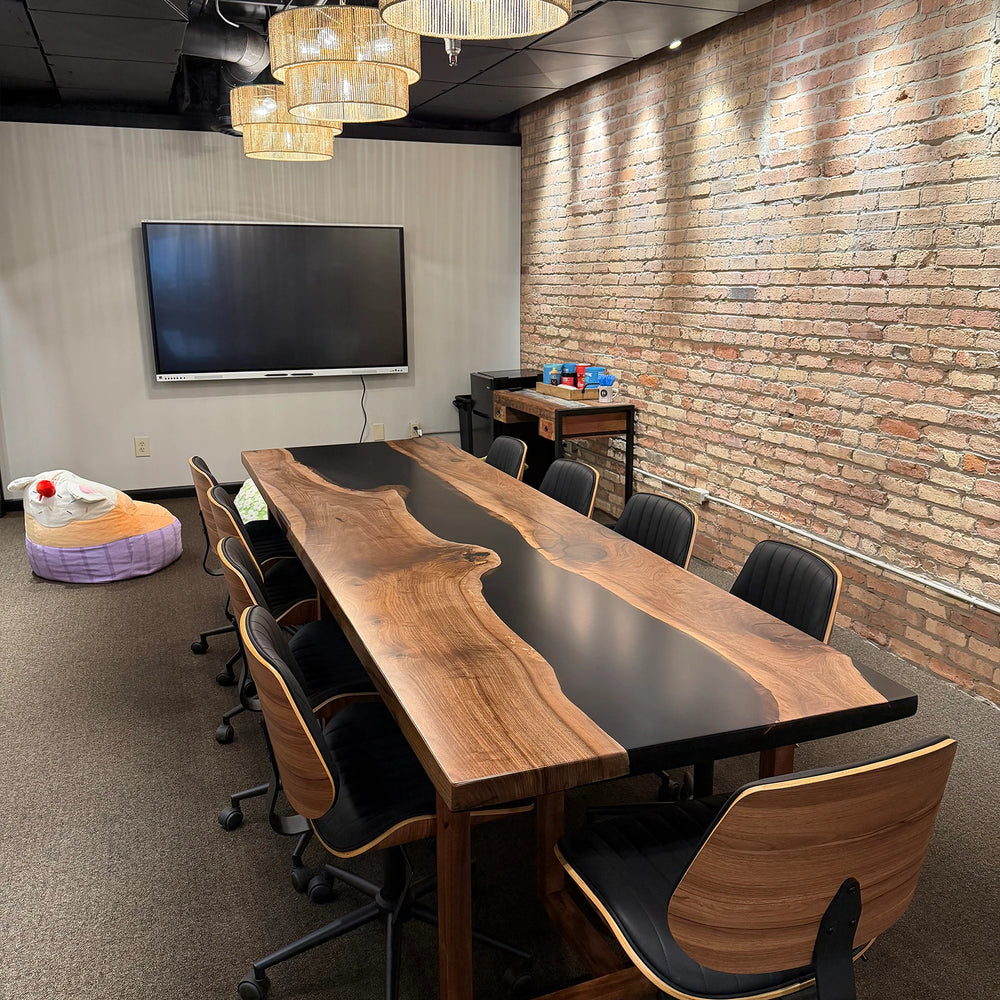 SeawaveTable custom black walnut conference table in modern industrial office interior with screen setup
