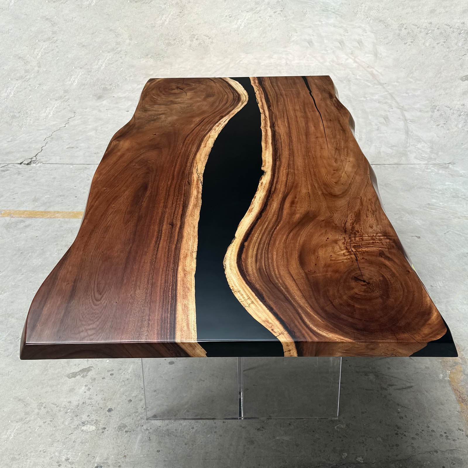 Detail shot of walnut live edge dining table with black epoxy river and natural wood character.