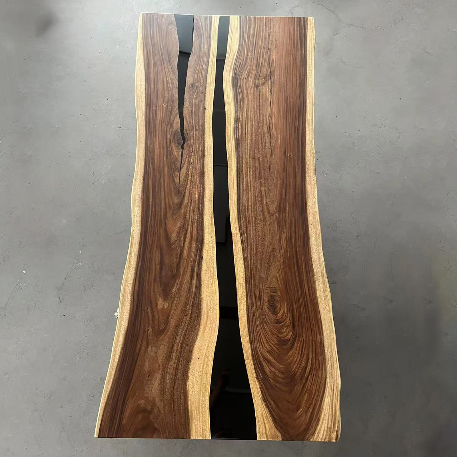 Close-up view of straight-edge walnut table showing seamless black epoxy river and wood texture.