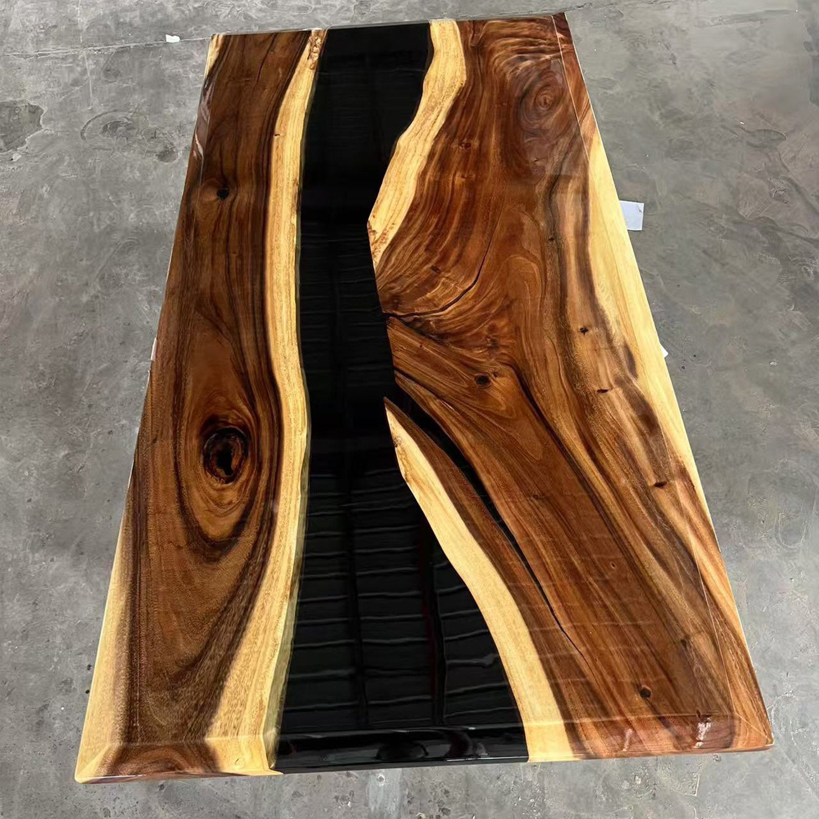 Side view of minimalist walnut table featuring white sapwood contrast and bold black epoxy river.