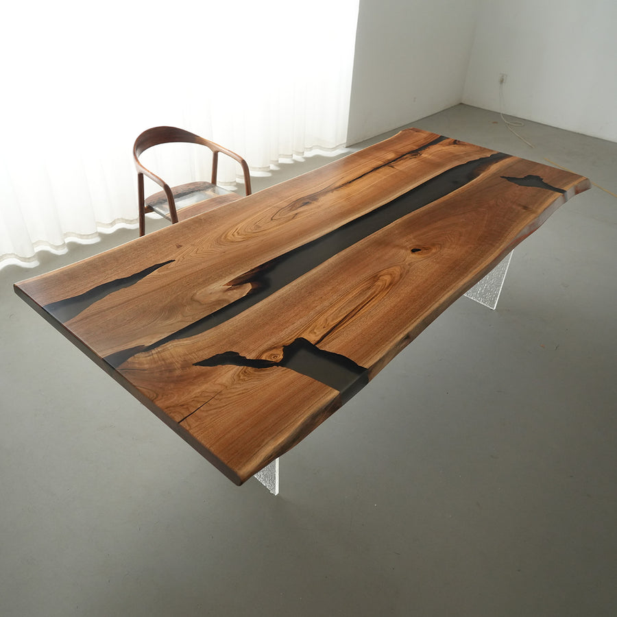 Black translucent epoxy resin flows through live edge walnut slab tabletop
